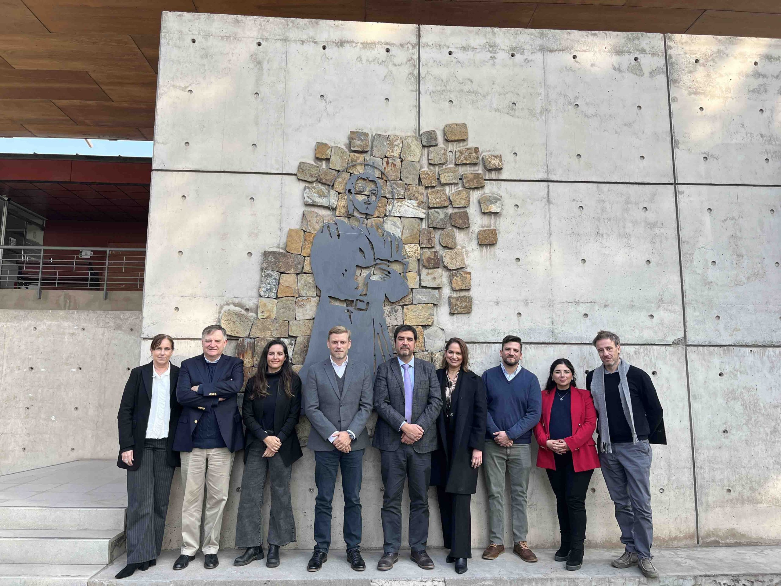 Grupo de profesionales frente a un mural de piedra.