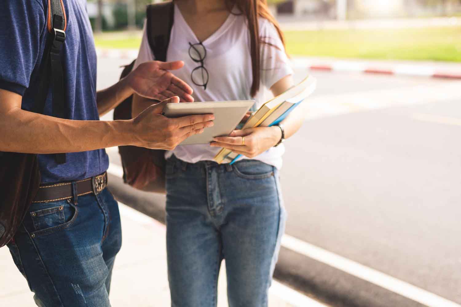 Estudiantes discutiendo sobre tecnología mientras sostienen libros y una tablet